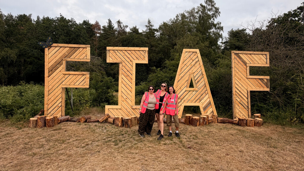 Kaboodle staff in front of Folk in a Field festival logo